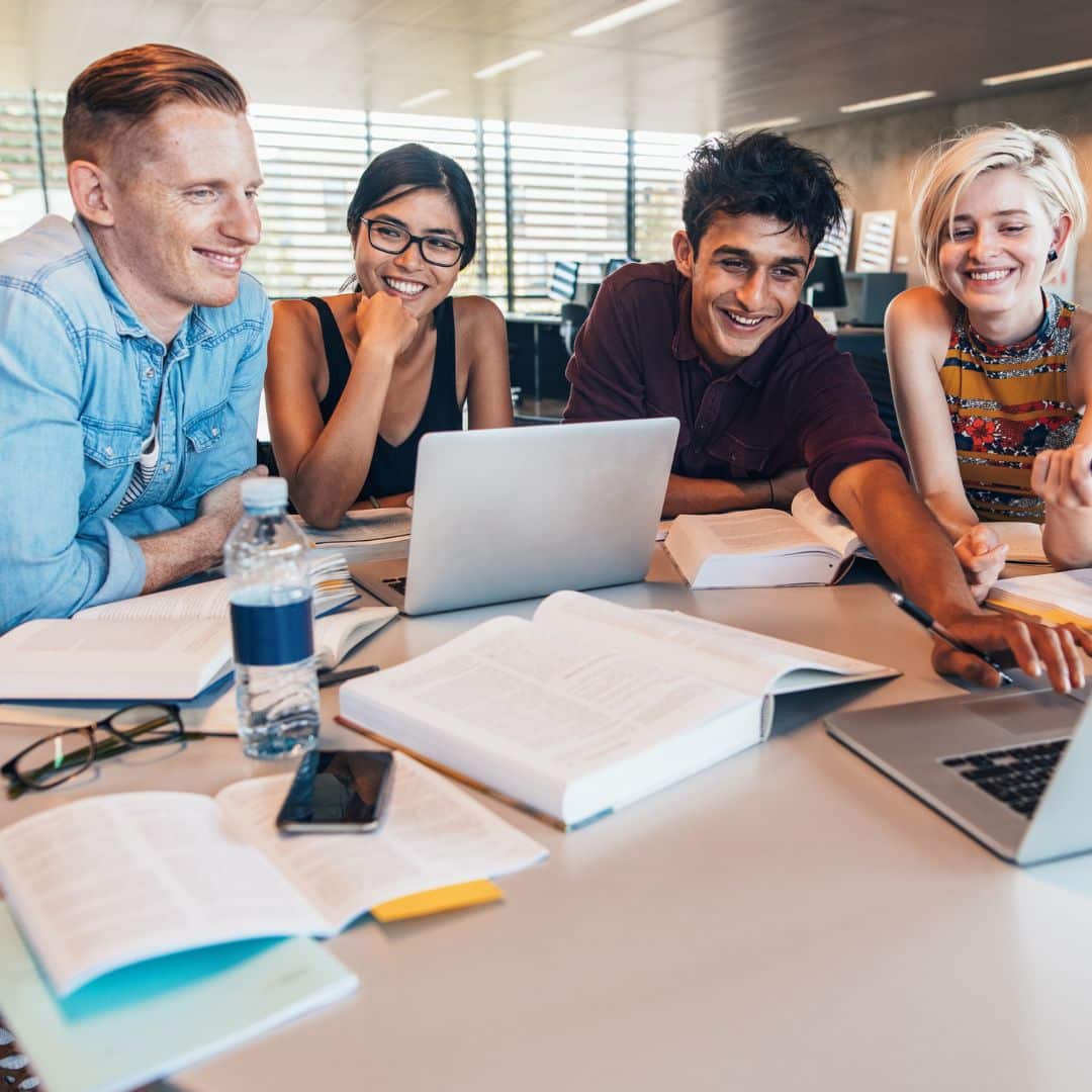 A group of students studying at a table with a laptop.